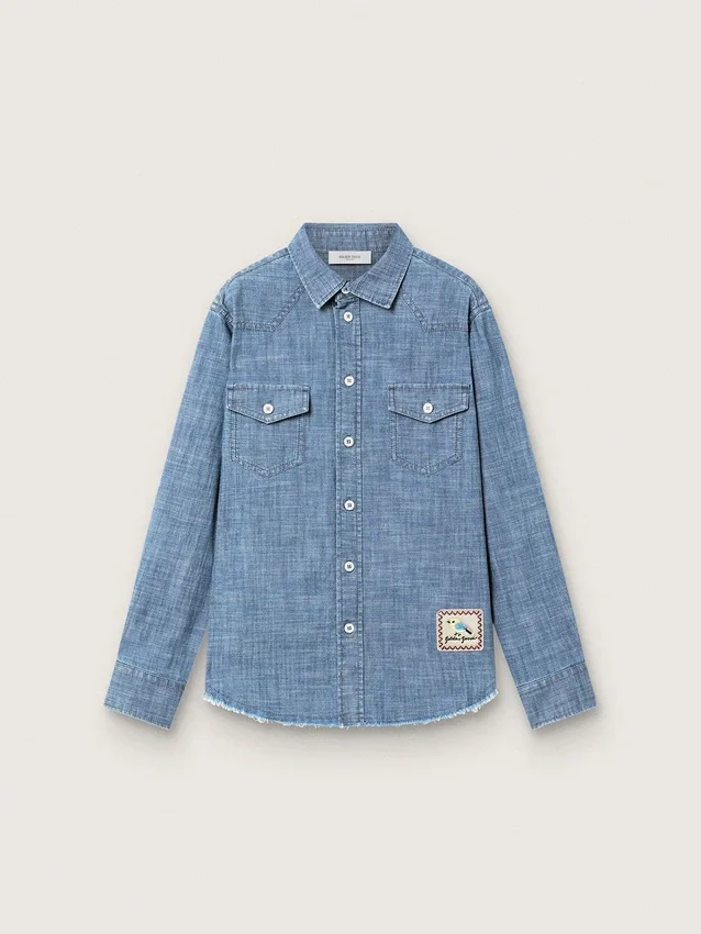 Journey unisex-skjorta i ljusblå bomullschambray med fransad nederkant och broderad patch