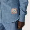 Journey unisex-skjorta i ljusblå bomullschambray med fransad nederkant och broderad patch