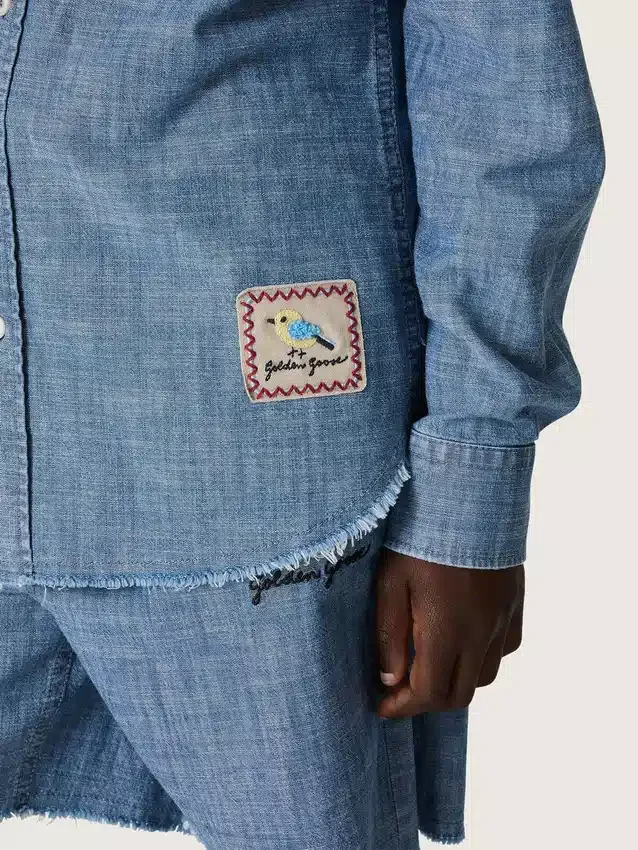 Journey unisex-skjorta i ljusblå bomullschambray med fransad nederkant och broderad patch