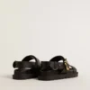 Lucy-sandal för dam i glansigt svart läder med guldspänne i metall