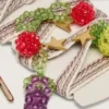 Skinn krämfärgade och duvgrå randiga broderade skosnören med tre fruktformade pärlberlocker