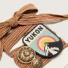 Skinn med broderade skosnören i vinrött och persika med patch och två berlocker